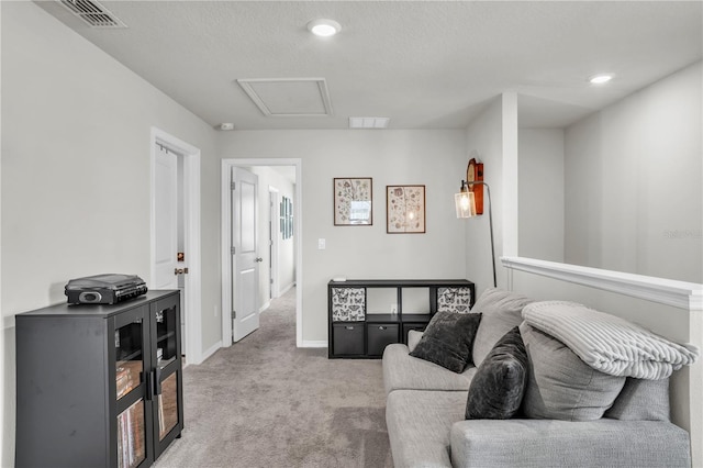 living area with attic access, light colored carpet, visible vents, and baseboards