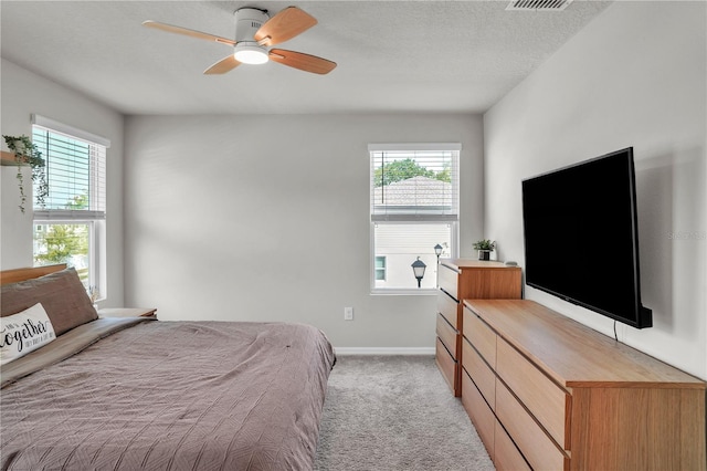 bedroom featuring a ceiling fan, light colored carpet, baseboards, and a textured ceiling