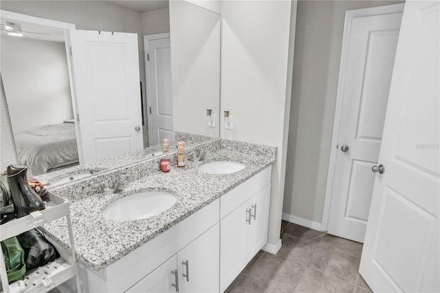 bathroom with a sink, baseboards, ensuite bath, and double vanity