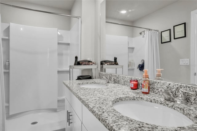 bathroom with a sink, a stall shower, and double vanity