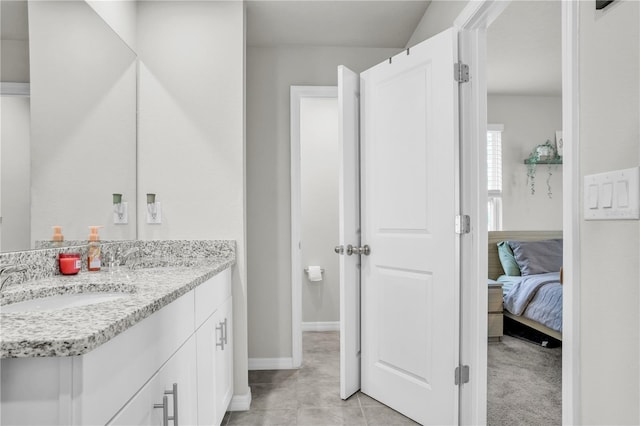 ensuite bathroom with tile patterned floors, vanity, ensuite bath, and baseboards