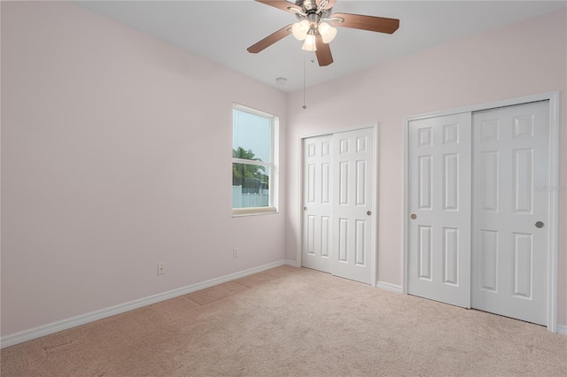 unfurnished bedroom featuring baseboards, two closets, ceiling fan, and carpet