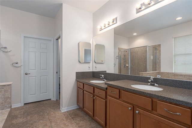 full bath with double vanity, tiled shower, baseboards, and a sink