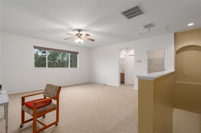 sitting room featuring arched walkways, visible vents, light colored carpet, and baseboards