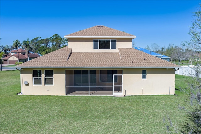 rear view of house with stucco siding, a shingled roof, a yard, and a sunroom