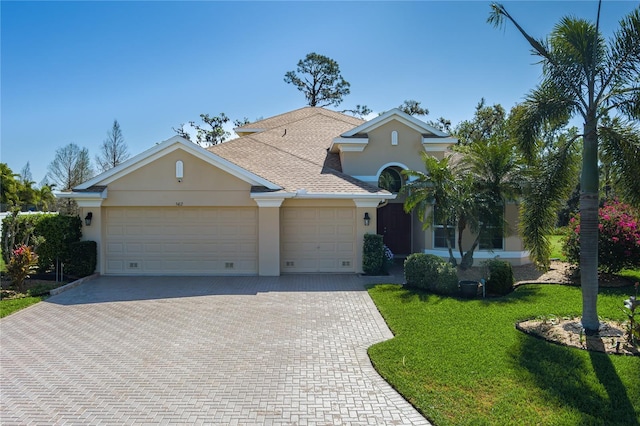 view of front of home featuring a front yard, roof with shingles, stucco siding, a garage, and decorative driveway