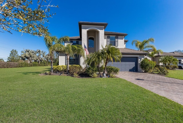 view of front of home featuring a garage, a tile roof, decorative driveway, and a front lawn