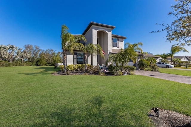 view of front of home featuring stucco siding, a front yard, and driveway