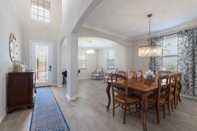 dining area featuring an inviting chandelier, crown molding, arched walkways, and baseboards