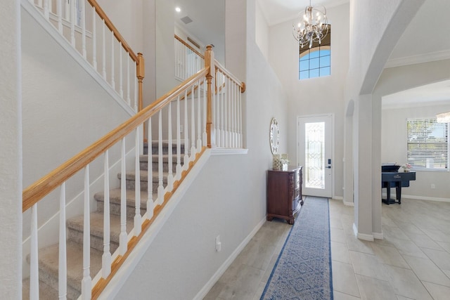 tiled entryway featuring stairway, baseboards, arched walkways, ornamental molding, and a notable chandelier