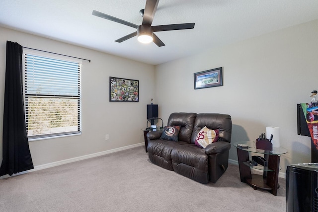 carpeted living room featuring baseboards and ceiling fan