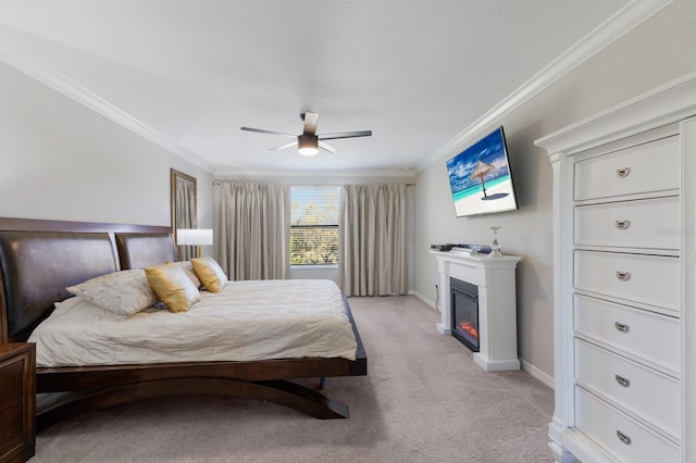 bedroom featuring a glass covered fireplace, baseboards, light carpet, and ornamental molding