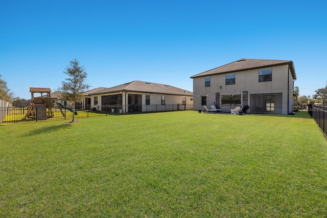 back of house with stucco siding, a lawn, a fenced backyard, and a playground