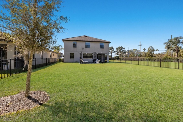 rear view of property with a lawn, a fenced backyard, and stucco siding