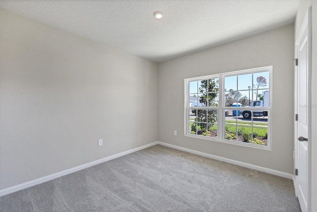 empty room with carpet flooring, baseboards, and a textured ceiling