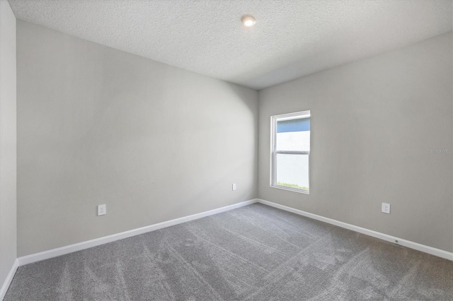 unfurnished room with a textured ceiling, baseboards, and dark colored carpet