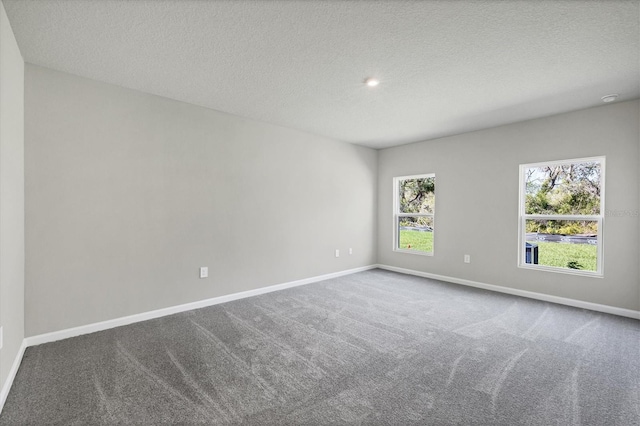 carpeted spare room with a textured ceiling and baseboards