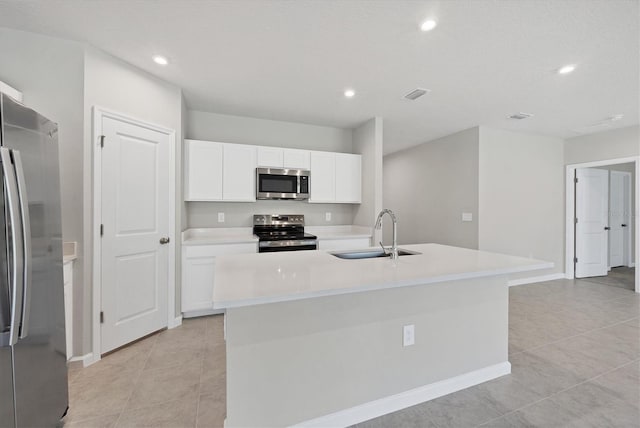 kitchen featuring visible vents, a kitchen island with sink, a sink, appliances with stainless steel finishes, and white cabinets