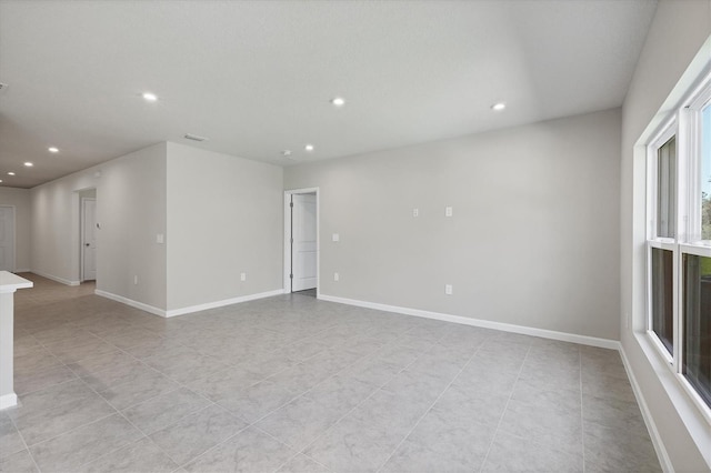 spare room featuring recessed lighting and baseboards