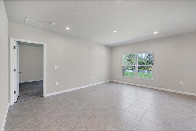 tiled empty room with recessed lighting, baseboards, visible vents, and a textured ceiling