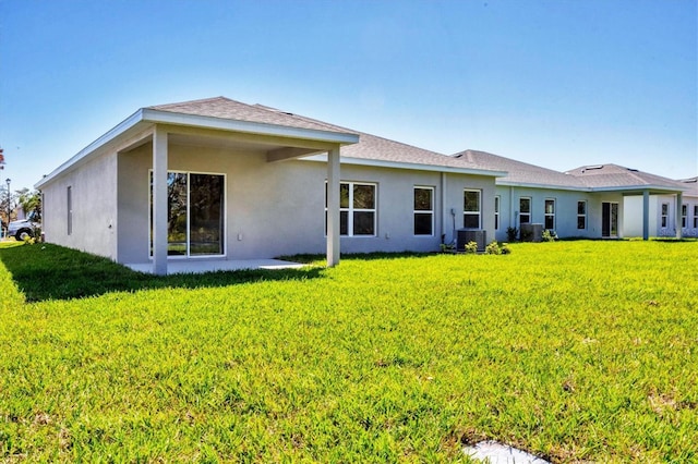 back of property with a yard, central AC, and stucco siding