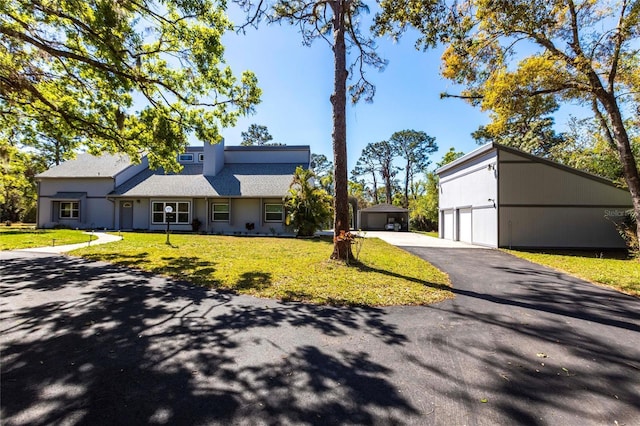 view of front facade featuring a garage, a front yard, and an outdoor structure