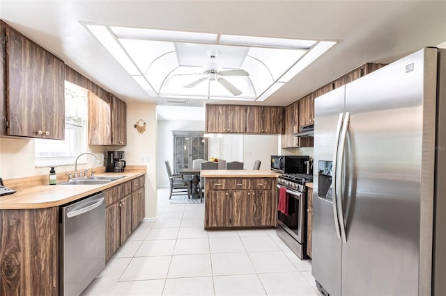 kitchen with light countertops, appliances with stainless steel finishes, a peninsula, a raised ceiling, and a sink