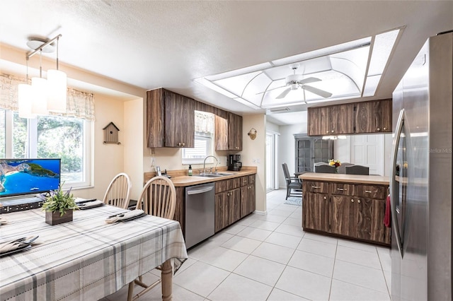 kitchen featuring appliances with stainless steel finishes, light countertops, light tile patterned floors, a raised ceiling, and ceiling fan