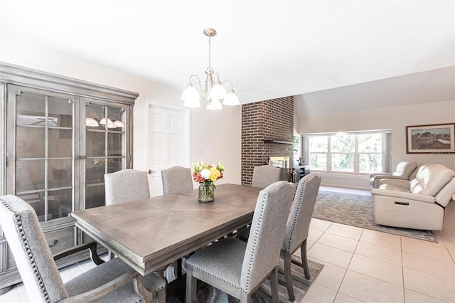 dining room with light tile patterned floors, a chandelier, and a fireplace