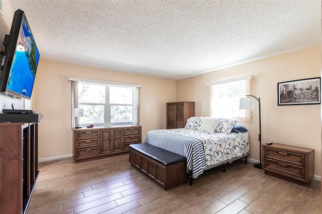 bedroom featuring baseboards, a textured ceiling, and wood tiled floor