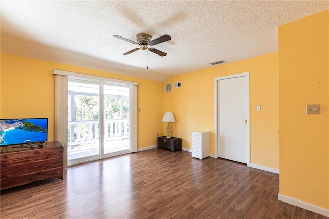 unfurnished living room featuring visible vents, baseboards, dark wood finished floors, a textured ceiling, and a ceiling fan