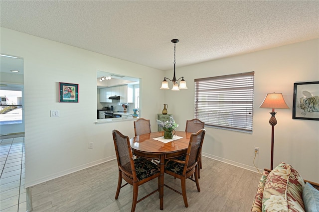 dining area with light wood-style flooring, baseboards, a chandelier, and a textured ceiling