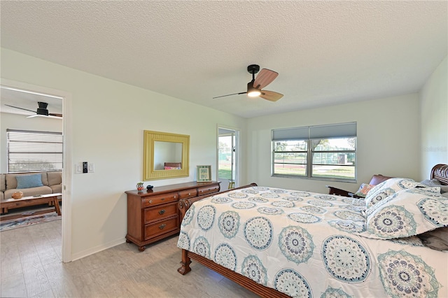 bedroom featuring light wood-style flooring, a ceiling fan, baseboards, and a textured ceiling