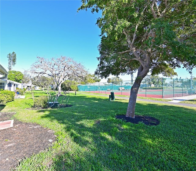 surrounding community with a tennis court, a yard, and fence