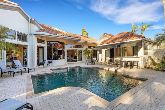 outdoor pool with a patio and outdoor dry bar