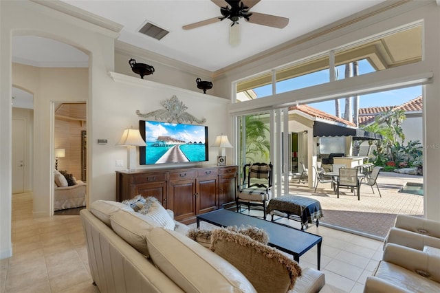 living area with visible vents, crown molding, light tile patterned floors, arched walkways, and a ceiling fan