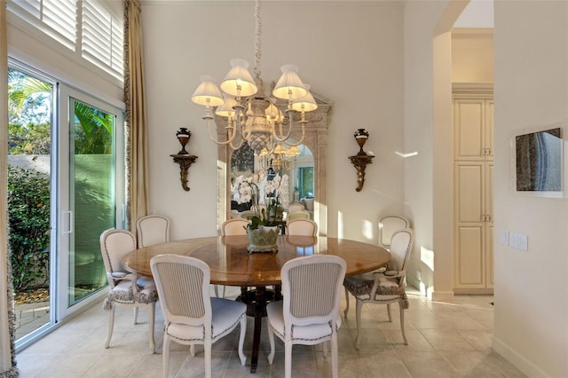 dining space with baseboards, arched walkways, an inviting chandelier, and light tile patterned flooring