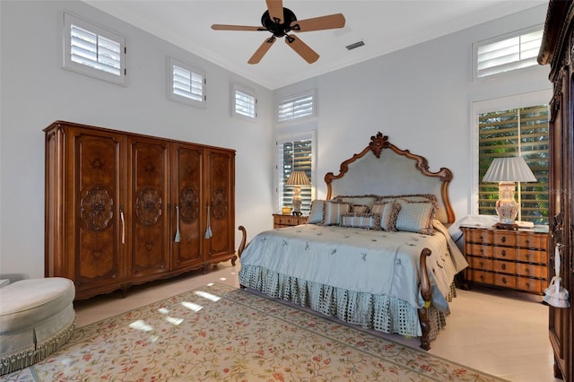 bedroom featuring visible vents, a high ceiling, a ceiling fan, and ornamental molding