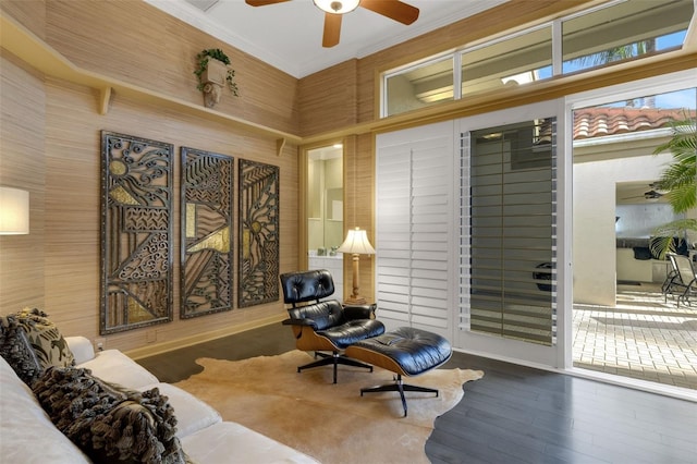 sitting room with ceiling fan, wood finished floors, and ornamental molding