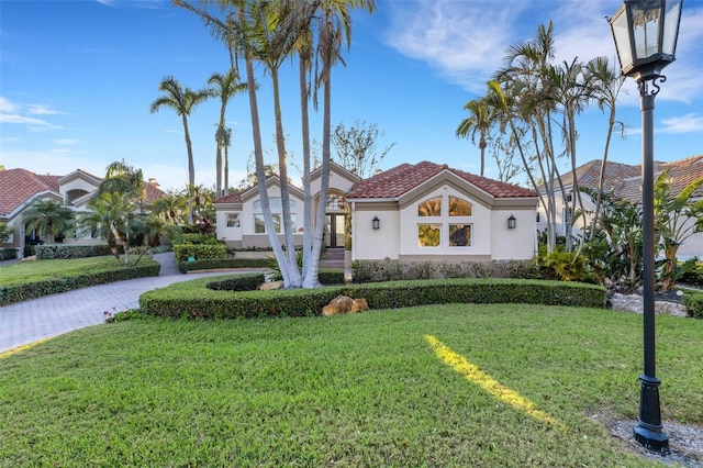 mediterranean / spanish home featuring stucco siding, a front yard, and a tile roof