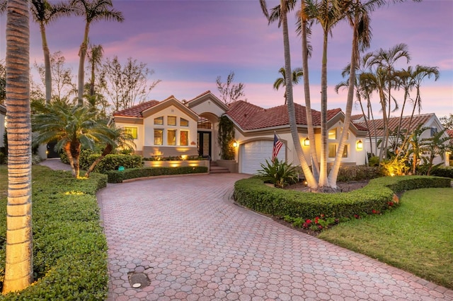 mediterranean / spanish-style home with decorative driveway, a garage, a tile roof, and stucco siding