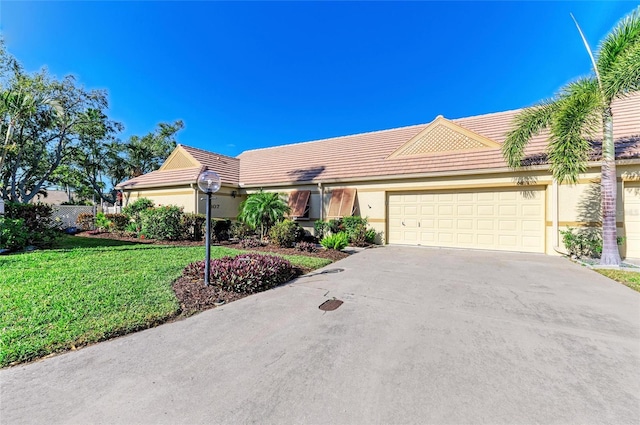 view of front of house with stucco siding, concrete driveway, an attached garage, a front yard, and a tiled roof