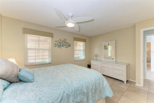 bedroom featuring light tile patterned floors, baseboards, a textured ceiling, and ceiling fan