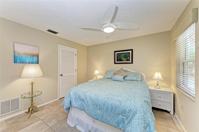 bedroom featuring light tile patterned flooring, visible vents, a textured ceiling, and a ceiling fan