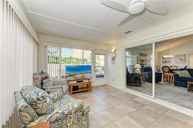 sunroom featuring visible vents, vaulted ceiling, and ceiling fan with notable chandelier