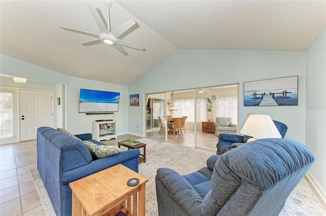 living area featuring a wealth of natural light, light tile patterned floors, a ceiling fan, and vaulted ceiling