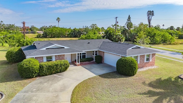 single story home with an attached garage, a front lawn, concrete driveway, and brick siding