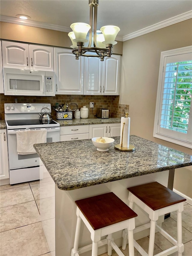 kitchen with white appliances, ornamental molding, white cabinets, a kitchen breakfast bar, and backsplash