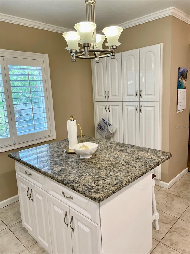 kitchen featuring dark stone counters, a kitchen island, ornamental molding, and white cabinets