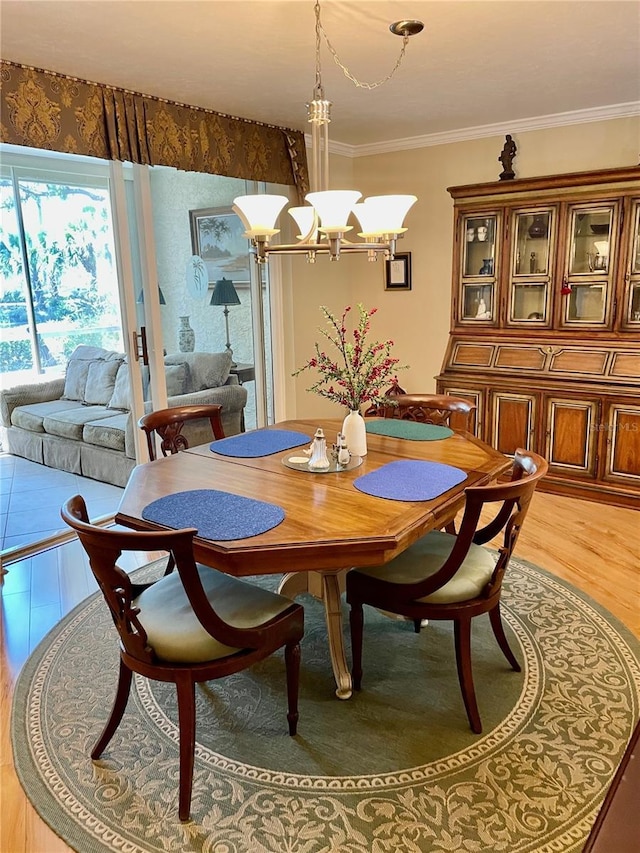 dining area featuring light wood finished floors, crown molding, and an inviting chandelier